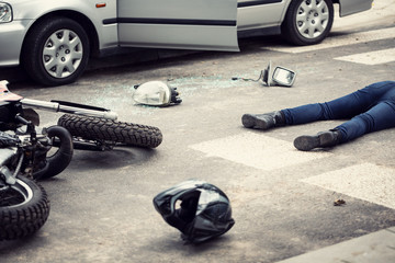 Motorcyclist helmet and motorbike on the street after collision with a car