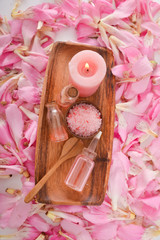 Pile of many pink petals background with and candle ,oil, spoon,candle, salt in basket