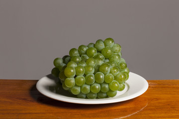 fresh green grapes on the wood table, grey background.