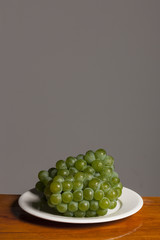 fresh green grapes on the wood table, grey background.
