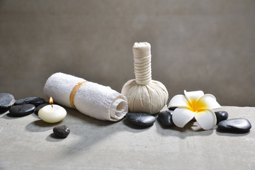 Fototapeta na wymiar black stones and candle , herbal ball,towel, frangipani on gray background