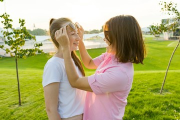Obraz premium Communication of the parent and adolescent, mother has fun with her daughter. Background green lawn, recreation and entertainment zone,