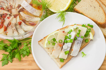 Open sandwich with pickled herring among of ingredients close-up