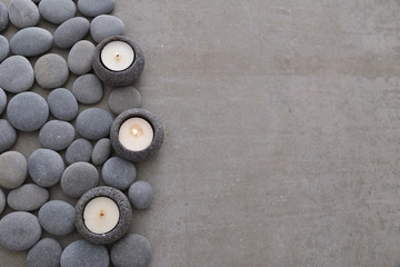 Pile of gray stones with three candle and grey background