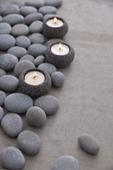 Obraz na płótnie Canvas Pile of gray stones with candle and grey background