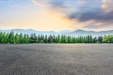 Fototapeta premium Empty asphalt square and mountain with forest scenery at sunrise