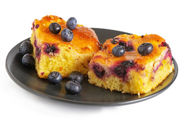 Two pieces of blueberry cake on a dark saucer isolated ob white