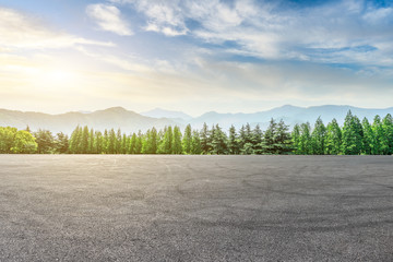 Empty asphalt square and mountain with forest scenery at sunrise
