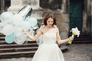 Pretty bride in her wedding dress holding balloons.