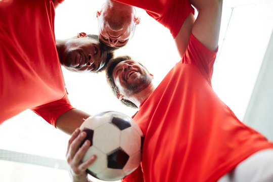 Three young footballers standing head to head close to each other symbolizing unity