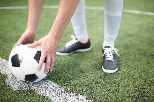 Soccer player putting ball on white line dividing football field before start of game