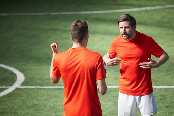 Two young footballers having argument during game of soccer at stadium