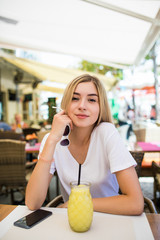 Young beautiful woman sitting in a cafe drinking a cocktail