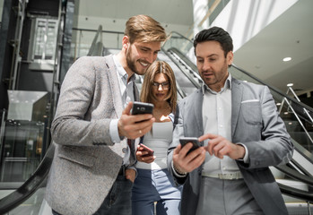 group of young businessmen looking at the screens of their smartphones