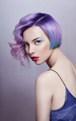 Portrait of a woman with bright colored flying hair, all shades of purple. Hair coloring, beautiful lips and makeup. Hair fluttering in the wind. Sexy girl with short  hair. Professional coloring