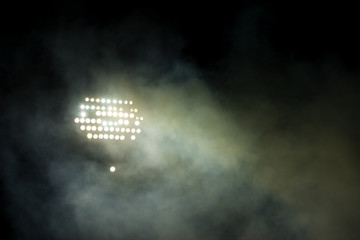 Light tower lit at a stadium during nightime.