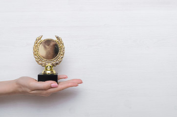 Golden medal award trophy in the female hand. Winner award ceremony.