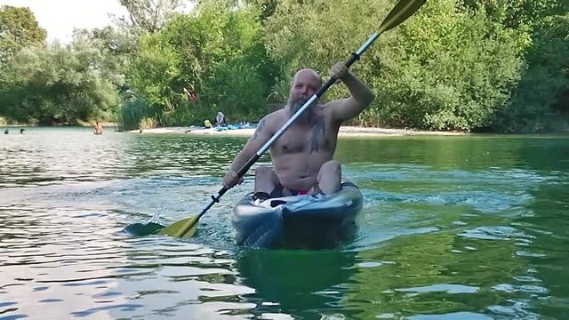 Slow motion of bearded man floating on kayak at daytime