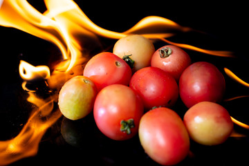 Burning tomato on black background