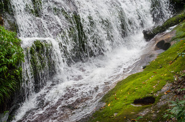 Waterfall flows down to earth with moss covered.