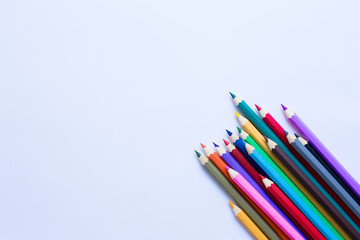 Set of coloured pencils on white paper. Top view. Free copy space.