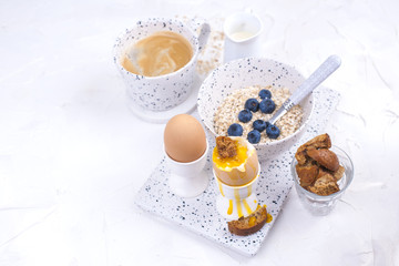 Delicious healthy breakfast of eggs, oatmeal with berries, coffee on a light background. Top view. Copy space.