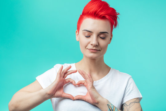 attractive awesome girl with closed eyes making a heart gesure. girl showing her feeling to a boy. isolated blue background