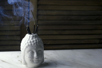 Buddha head with flower, incense stick  on a wooden background