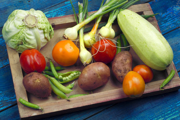 fresh organic farm vegetables on a wooden tray top view blue wooden boards for background ingredients for vegetable stew vegetarian food concept