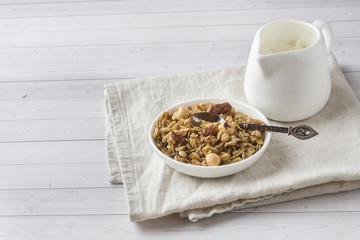Dry Breakfast of oat flakes, granules and nuts. Muesli in a plate and a milk jug with yogurt.