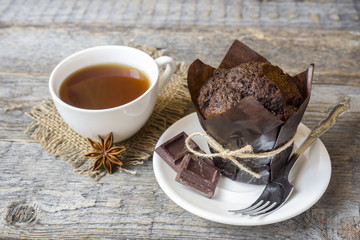 Chocolate muffin and a Cup of coffee on a wooden background.