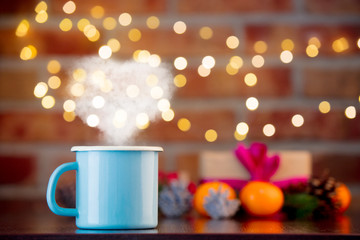 cup of hot drink with heart shape steam on background with fairy lights in bokeh. Christmas Holiday season
