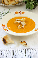 Vegan carrot or pumpkin cream soup served with croutons and thyme. Rustic style.