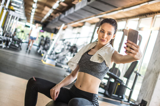 Young sportswoman taking selfie after sports training in gym