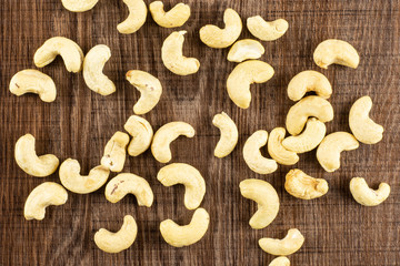 Lot of whole raw cashew nut flatlay on brown wood