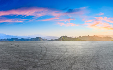 Empty asphalt road and great wall with mountains at sunset
