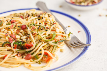 Healthy vegan pasta with zucchini, tomatoes and nuts.