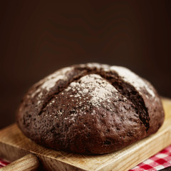 Fresh bread on dark wood  background with cpyspace. Crisp. Homemade loaf of  bread on cuttinf board, close up.