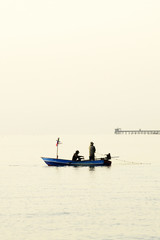 Fototapeta na wymiar Fishermen out fishing at sunrise in the sea, amidst the clouds and the sky is beautiful