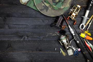 Photo sur Plexiglas Pêcher Fishing rods and reels, fishing tackle on black wooden background.