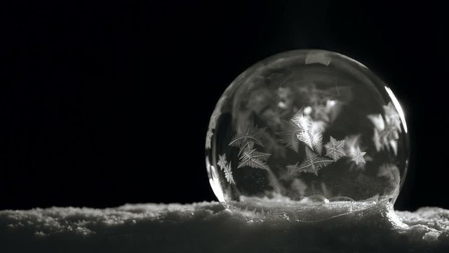 Ice crystal ball freezing on snow on black background