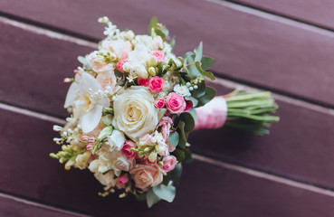 Wedding bouquet on a wooden background. Pink and cream roses.
