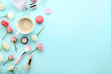 Flowers with cup of coffee and makeup cosmetics on blue background