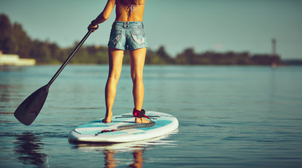 SUP Stand up Surf girl with paddle at sunset - obrazy, fototapety, plakaty