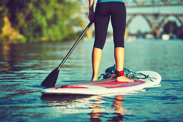 SUP Stand up Surf girl with paddle at sunset