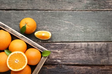 Zelfklevend Fotobehang Orange fruit with green leafs in crate on grey wooden table © 5second