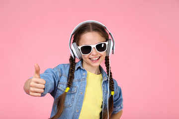 Young girl with headphones on pink background