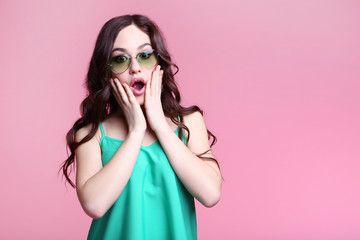Beautiful young woman with sunglasses on pink background