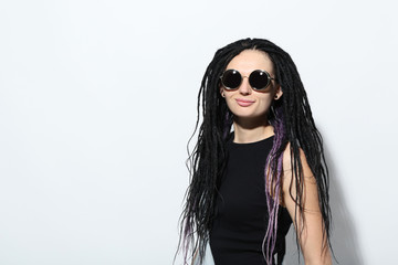 Young woman with dreadlocks and sunglasses on white background