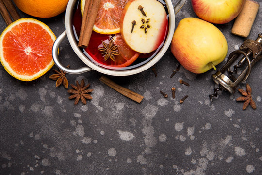 Preparation of red mulled wine with orange, apple, cinnamon, spicy autumn drink in the pan. Copy space for text, top view